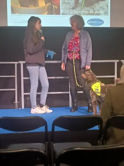 Kvinna står med sin hund på en scen 