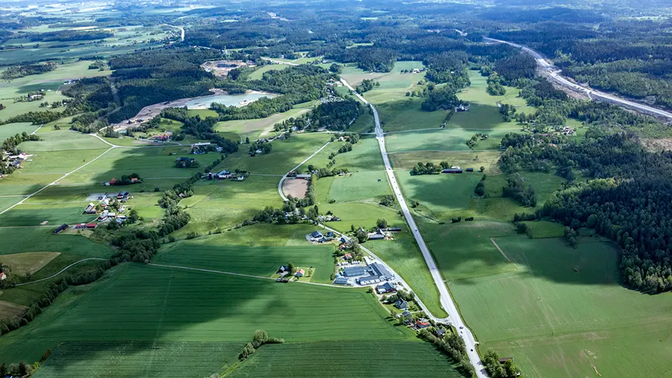 Flygfoto över åkrar, väg, bebyggelse