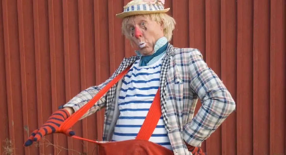 Clown med stora byxor och röd näsa