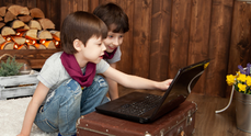 Två barn som sitter och tittar på en dator.